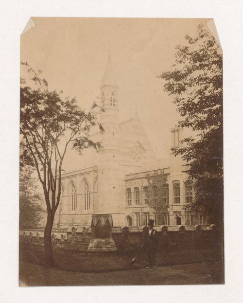 Partial view of a church taken from outside the churchyard wall with a man wearing a top hat in the foreground, England [?]