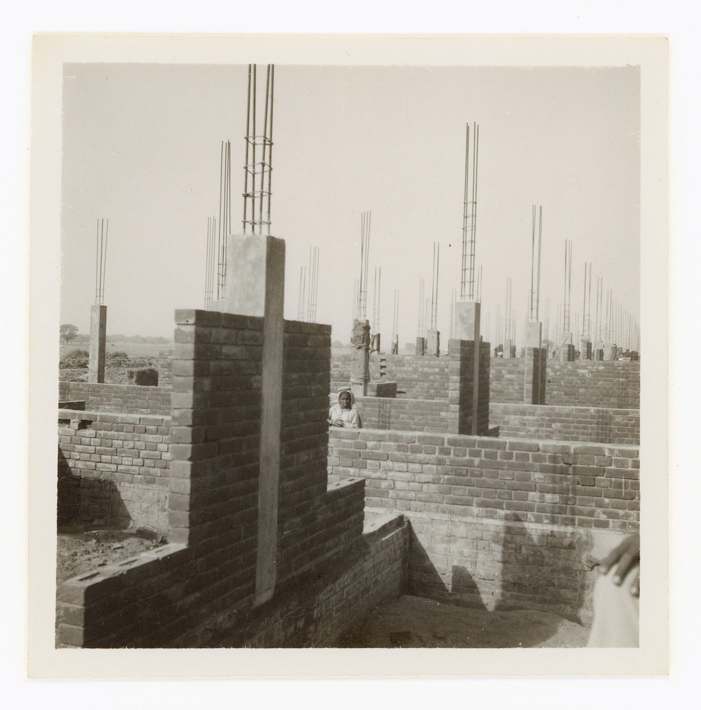 View of brick and concrete buildings under construction with worker in background, Chandigarh, India