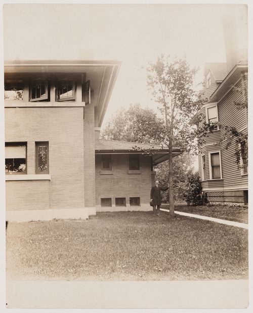 Portrait of Darwin D. Martin [?] standing beside the Darwin D. Martin House, Buffalo, New York