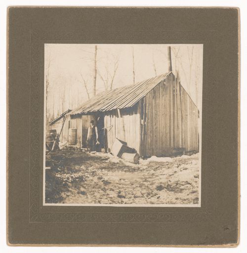 View of sugar shack showing a man standing in front of open door, Québec [?], Canada