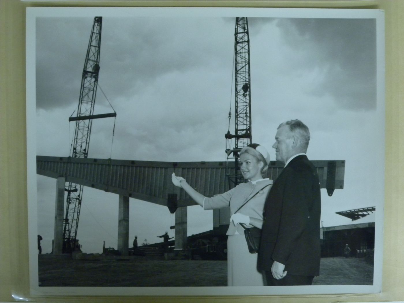 Portrait of Rear Admiral Hugh F. Pullen and of an unidentified woman with the Atlantic Provinces' Pavilion under construction as background, Expo 67, Montréal, Québec