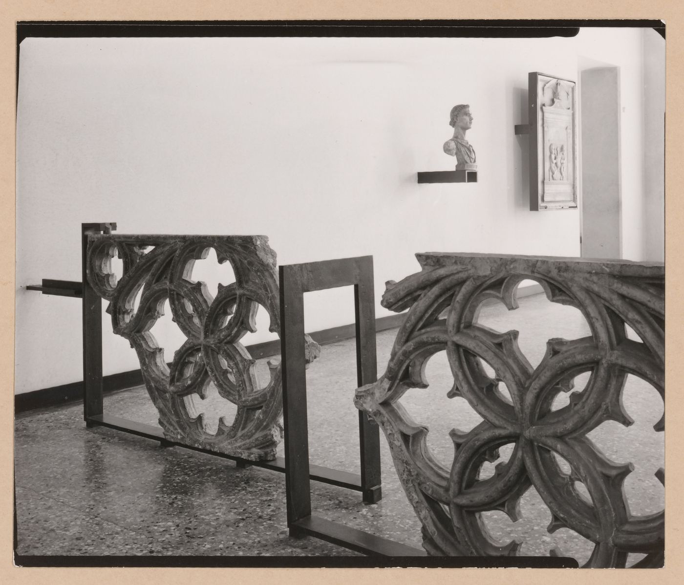 Interior view of a gallery showing fragments of stone tracery with a bust and reliefs in the background, Museo Correr, Venice, Italy