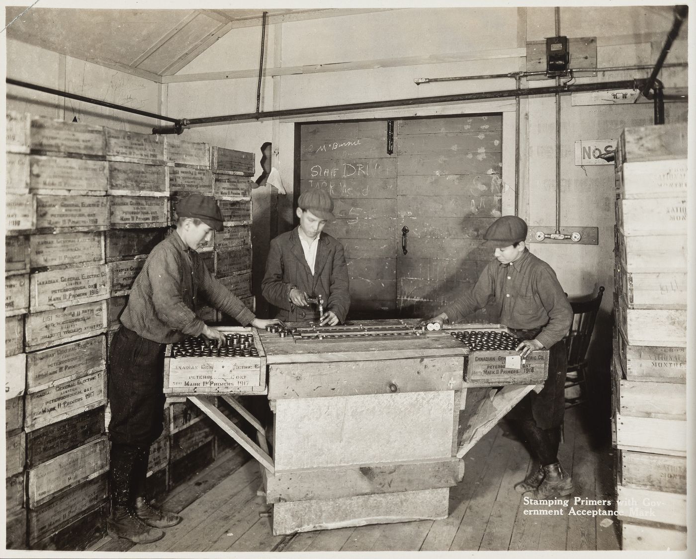 Interior view of workers stamping primers with government acceptance mark at the Energite Explosives Plant No. 3, the Shell Loading Plant, Renfrew, Ontario, Canada