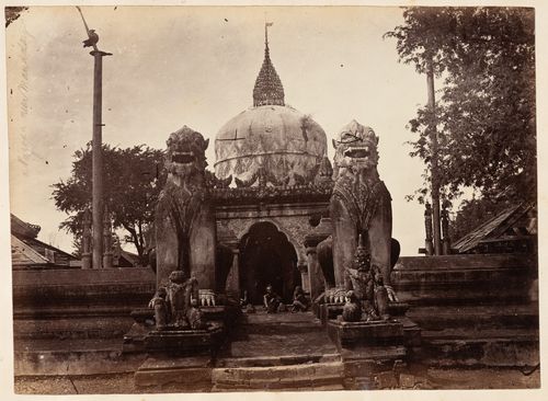 View of an entrance gateway and statues of lions with a temple in the background, near Mandalay, Burma (now Myanmar)