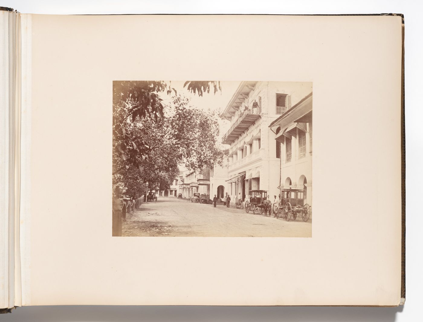 View of Raffles Place (formerly Commercial Square) showing businesses, including Hoon Keat & Co., the Singapore Dispensary, John Little & Co., and Geok Teat & Co., with the Oriental Bank in the right foreground, Singapore