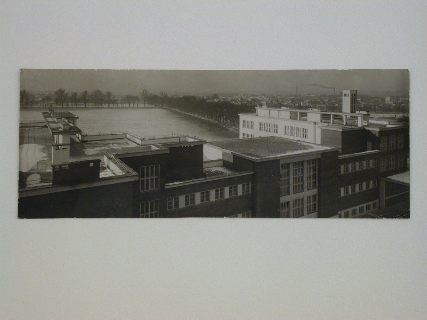 Panoramic view of building rooftops and a field with the city in the right background, Hradec Králové, Czechoslovakia (now Czech Republic)