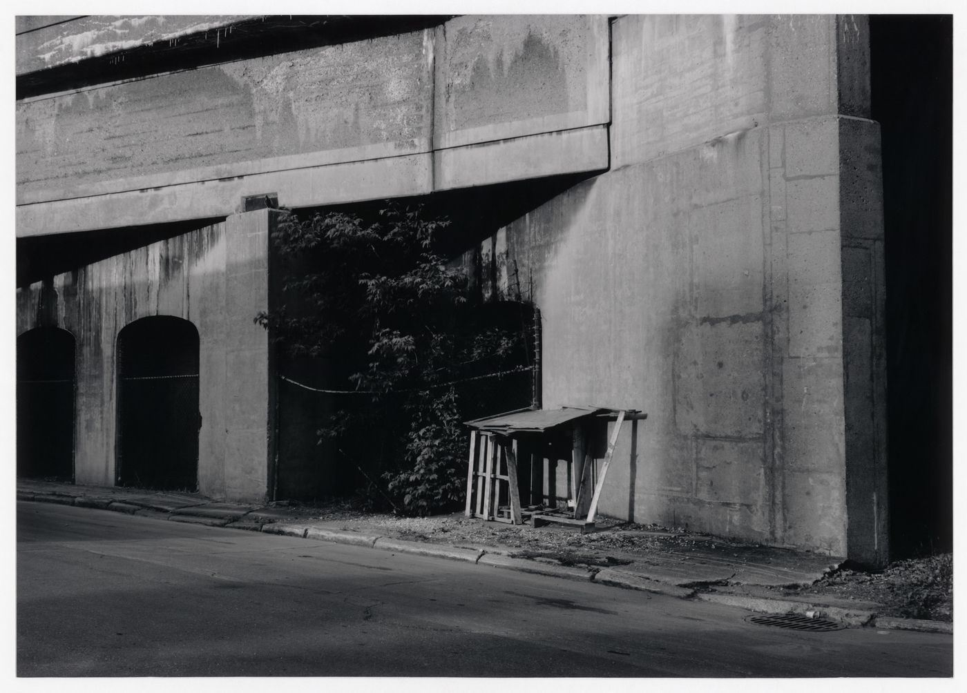 Field Work in Montreal: View of a shack-like structure, viaduct, arches, chain-like fence, sidewalk and street, Montréal, Québec