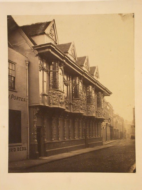 View of city street, elaborately decorated facade of 3-storey building