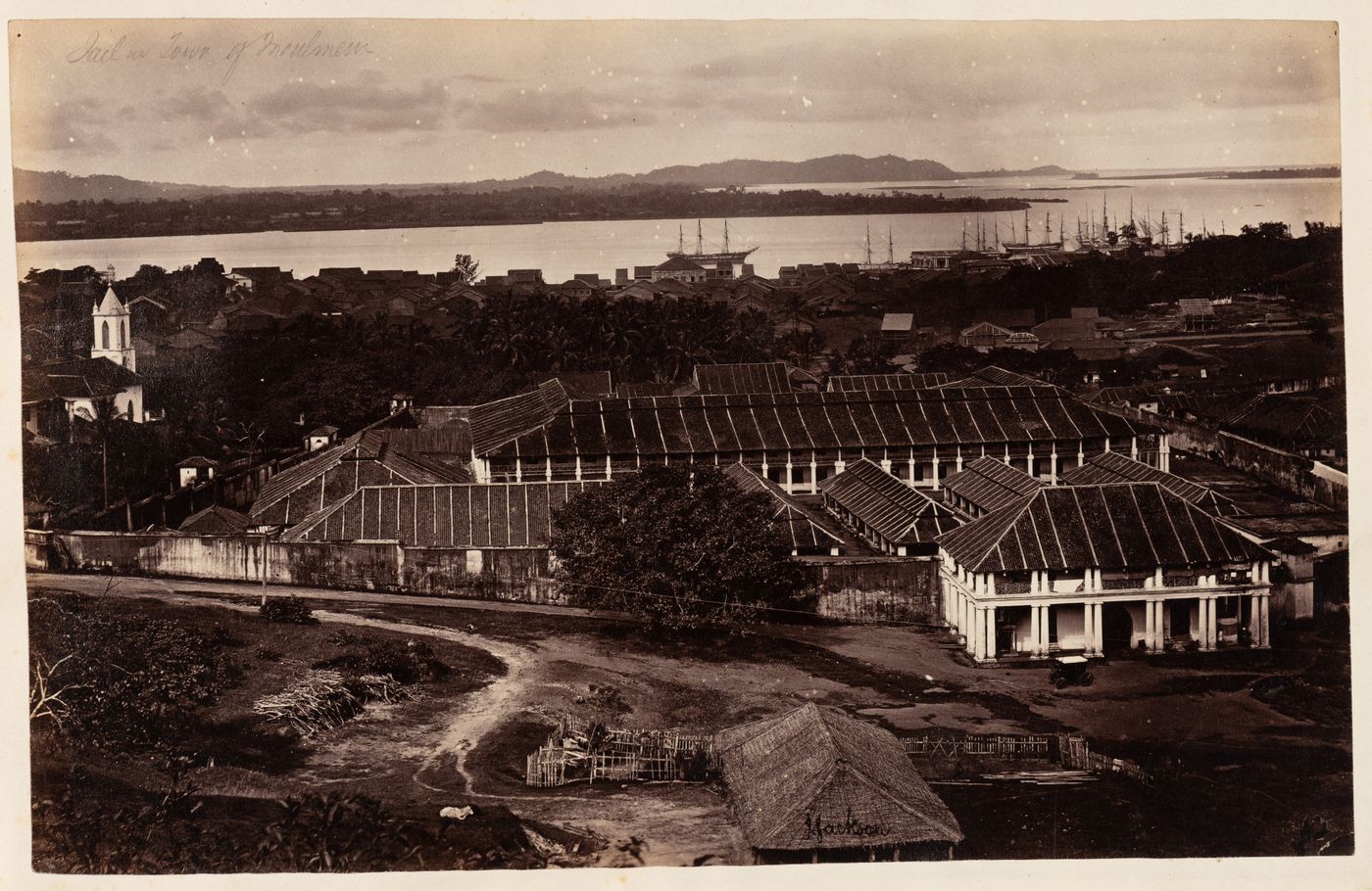 View of the Jail with the Roman Catholic Convent and Church of St. Patrick on the left and houses, a harbour and seaway in the background, Moulmein, Burma (now Myanmar)