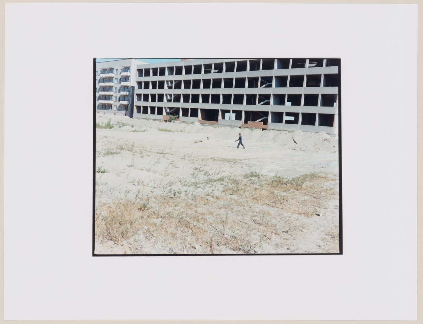 View of a building under construction, a vacant lot, and a person, Kaliningrad, Kaliningradskaia oblast', Russia (from the series "In between cities")