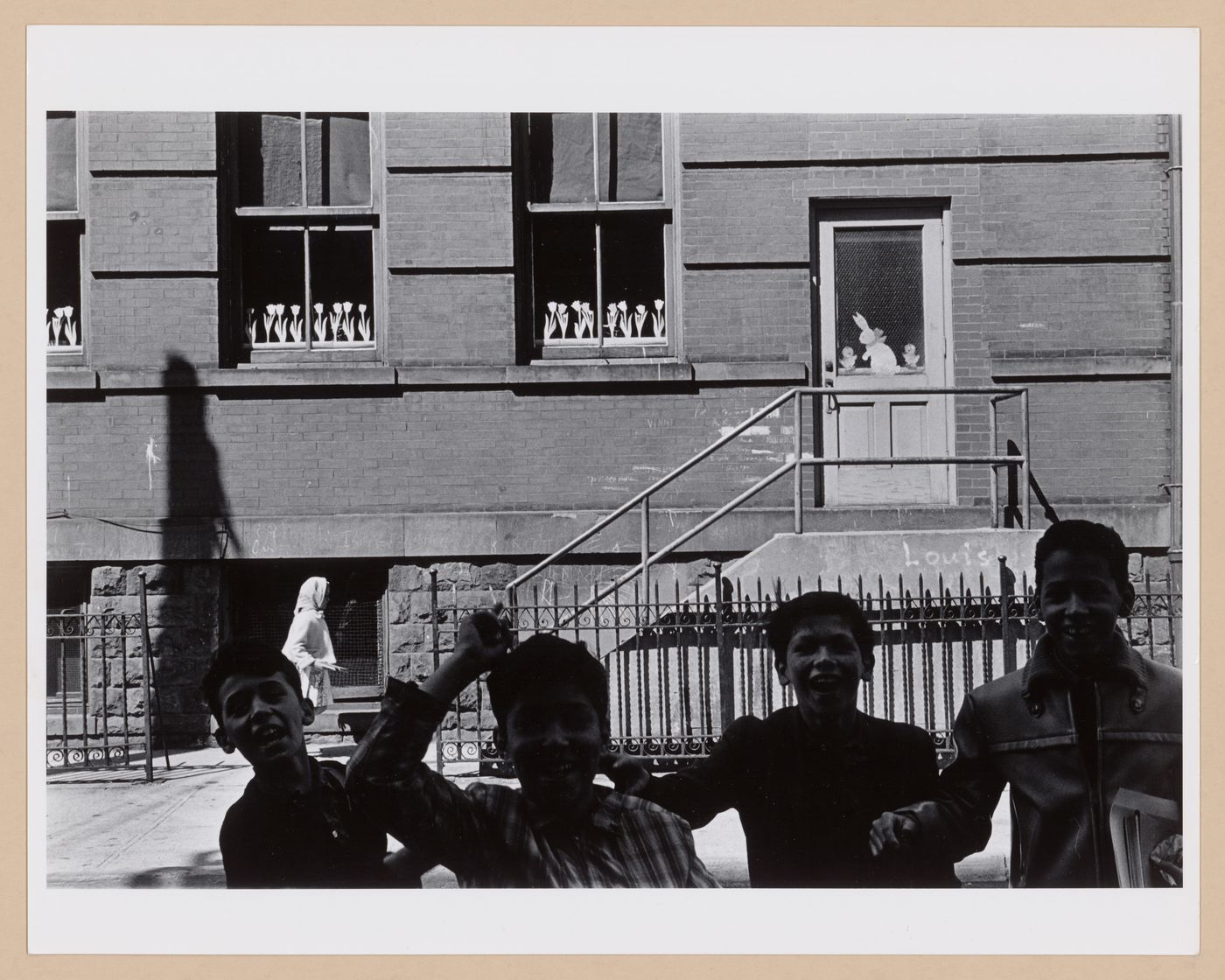 Partial view of a façade of a school [?] with children laughing in the foreground, Hoboken