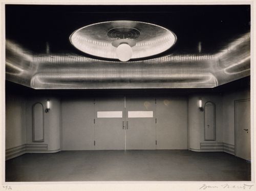 Interior view of a room with a large circular light fixture and a reflective ceiling
