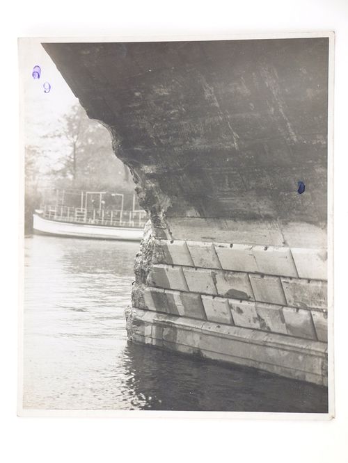 View of damage to the base of a stone arch bridge over water, United Kingdom
