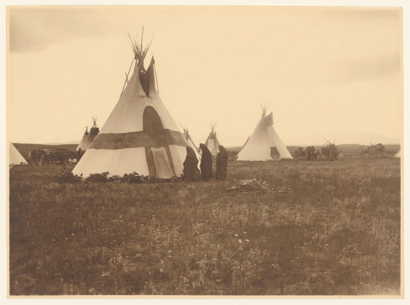 View of three women showing tipis and wagons, United States