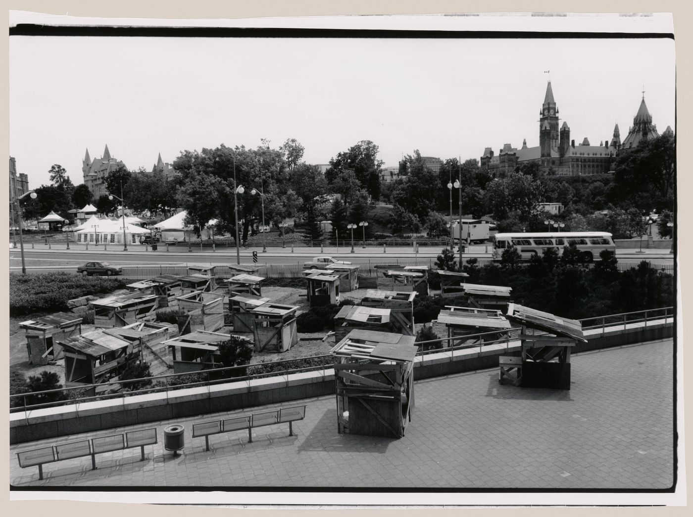 View of the installation "Favela in Ottawa", comprising wooden shack-like structures in the Taiga Garden of the National Gallery of Canada, showing the Parliament Buildings, Ottawa, Ontario