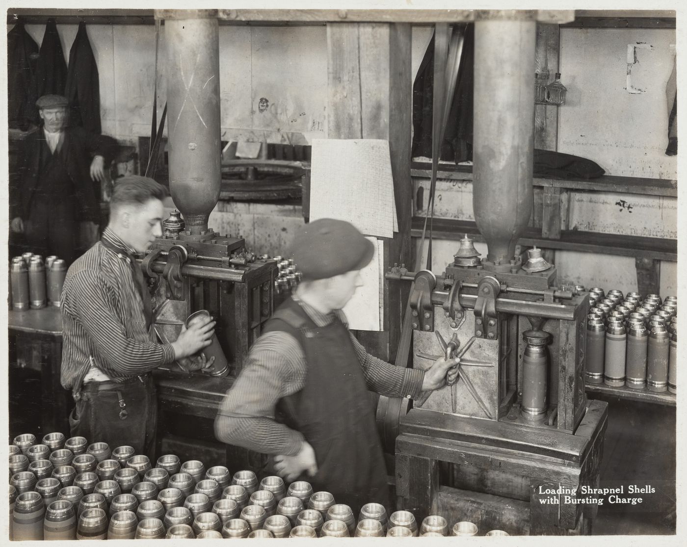 Interior view of workers loading shrapnel shells with bursting charge at the Energite Explosives Plant No. 3, the Shell Loading Plant, Renfrew, Ontario, Canada