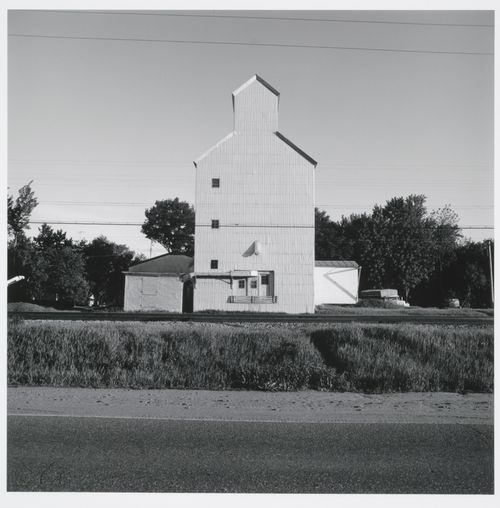 Grain elevator with corrugated metal siding, road and train tracks in foreground, Lake City, Wisconsin