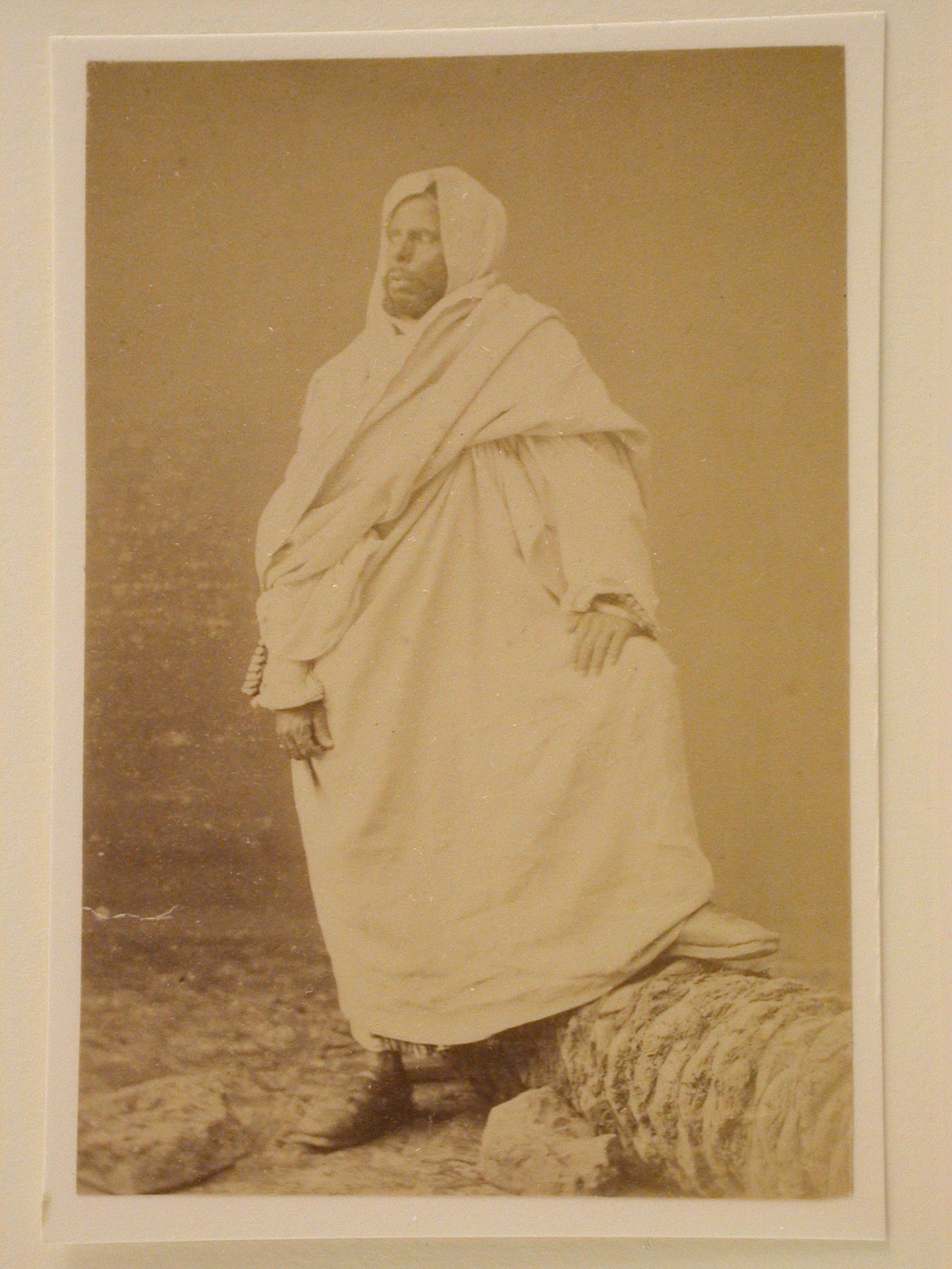 Standing white robed man with foot on rock