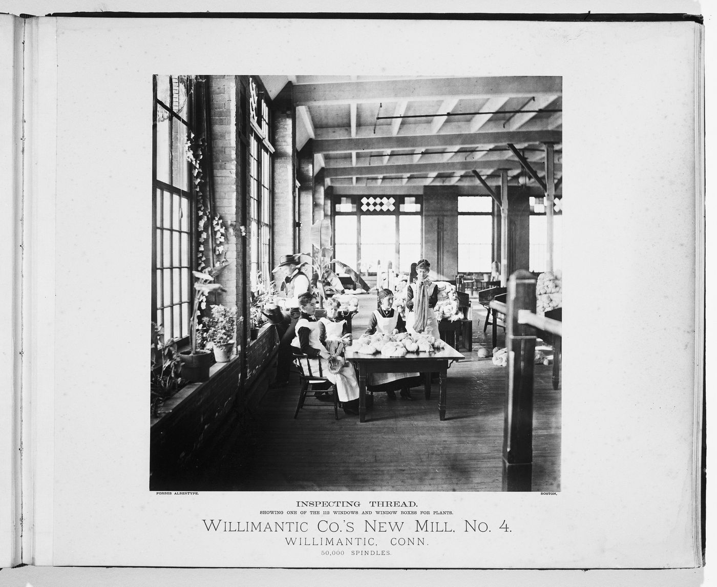 Interior view of women around a table to inspect threat, and a man watering plants, Willimantic Company’s new mill, no. 4, town of Willimantic, now Windham, Connecticut, United States