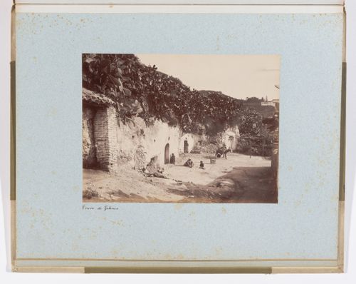 View of residents in front of troglodyte houses with Generalife in far background, Sacromonte, Granada, Spain
