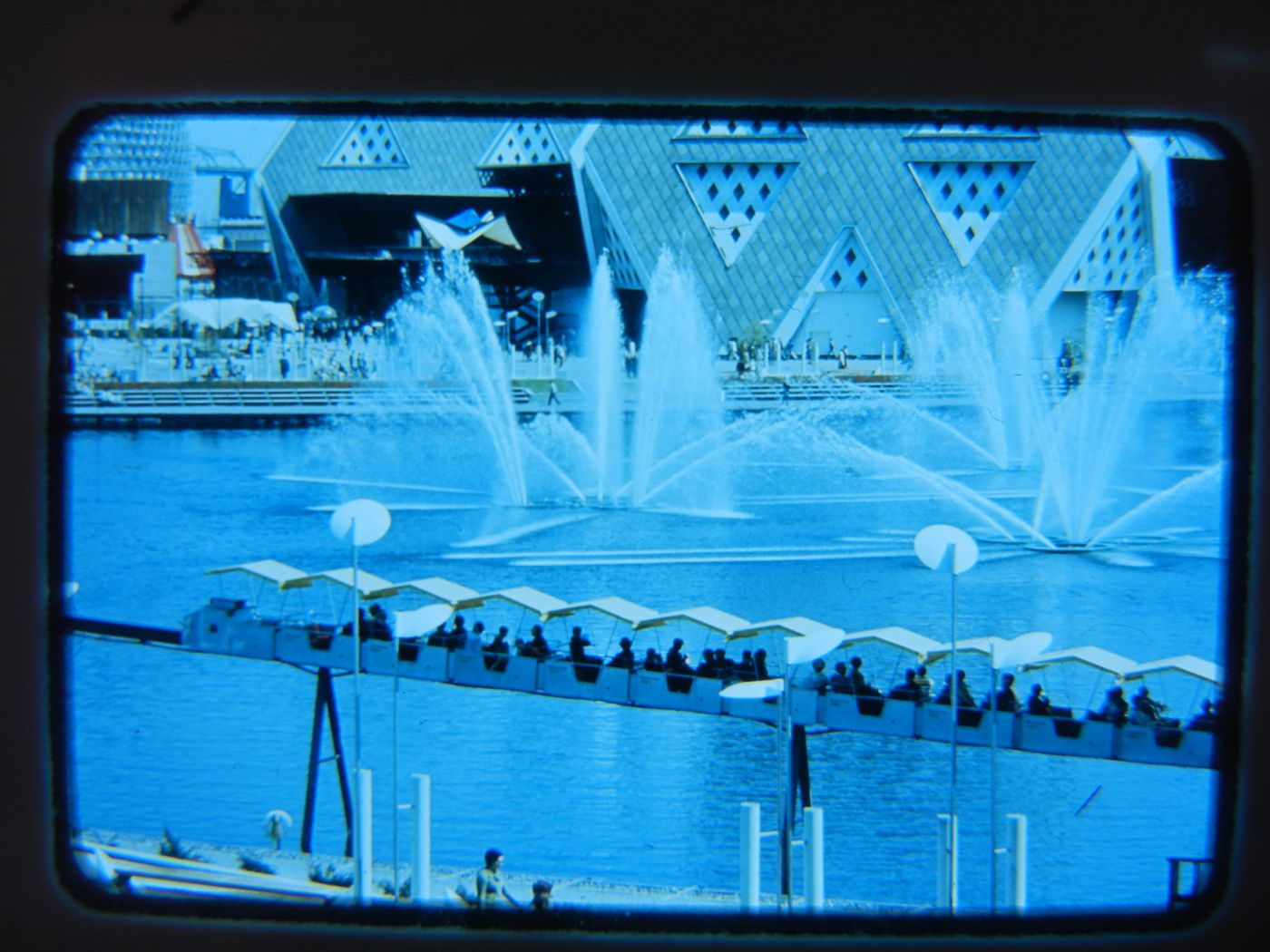 Aerial view of the Fountain of the Swans with a minirail in foreground and Man the Explorer Pavilion in background, Expo 67, Montréal, Québec