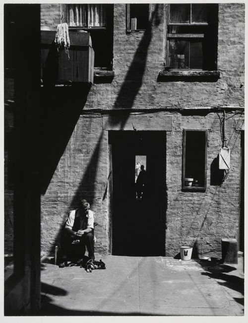 View of backyard and doorway of St. Joseph's House, with figure in door and seated man with dog, New York City, New York