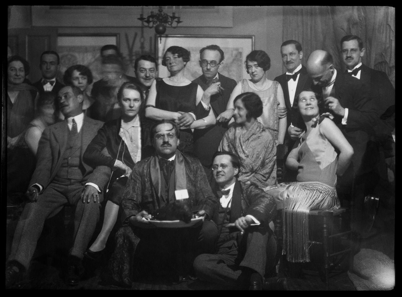 Portrait de groupe d'invités avec Ernest Cormier assis sur le sol lors d'une soirée
