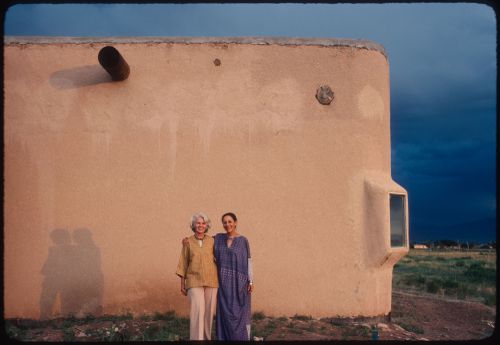Anne Alpert and Luchita Mullican in front of an adobe building, Taos, New Mexico