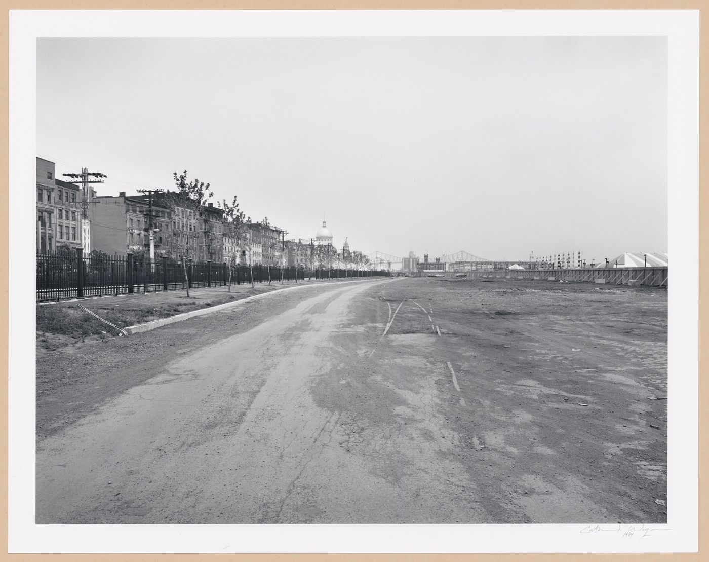 View of an empty lot in the Port of Montréal showing commercial buildings and rue de la Commune on the left with the Bonsecours Market and Pont Jacques-Cartier in the background, Québec