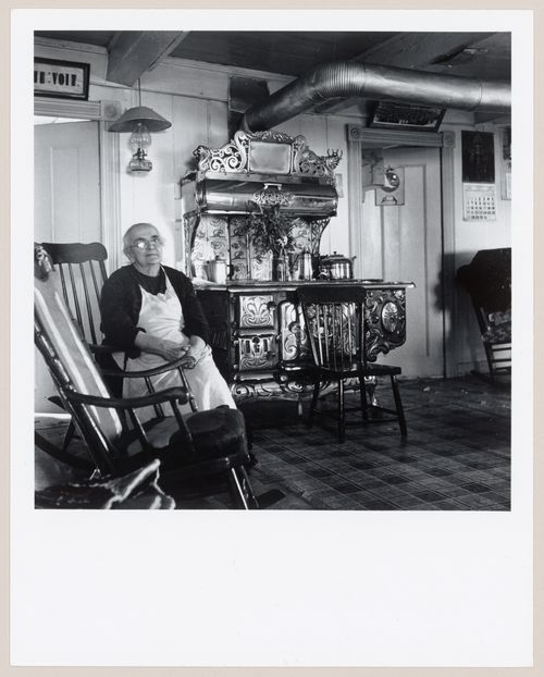 La conteuse Marie Desmeules assise près du poêle à bois dans sa cuisine, L'Isle-aux-Coudres, Charlevoix, Québec