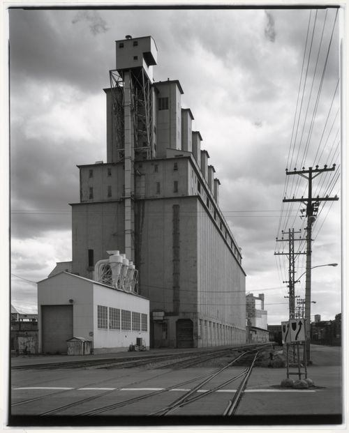 View of the east and north façades of Grain Elevator No. 2 (now demolished) showing the shed and railway tracks in the foreground, and Grain Elevator No. 1 (now demolished) in the background, Port of Montréal, Québec