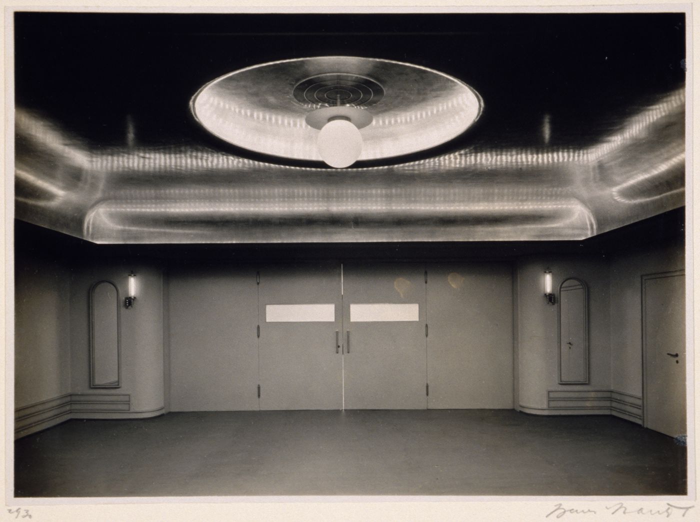 Interior view of a room with a large circular light fixture and a reflective ceiling