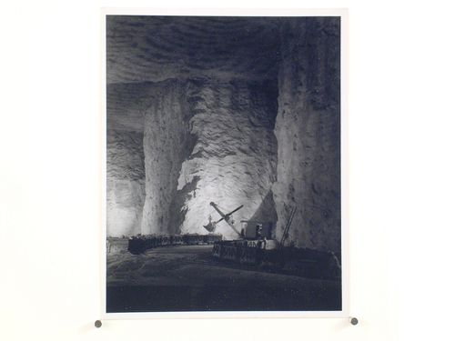 Interior of mine with men working crane and cars filled with ore