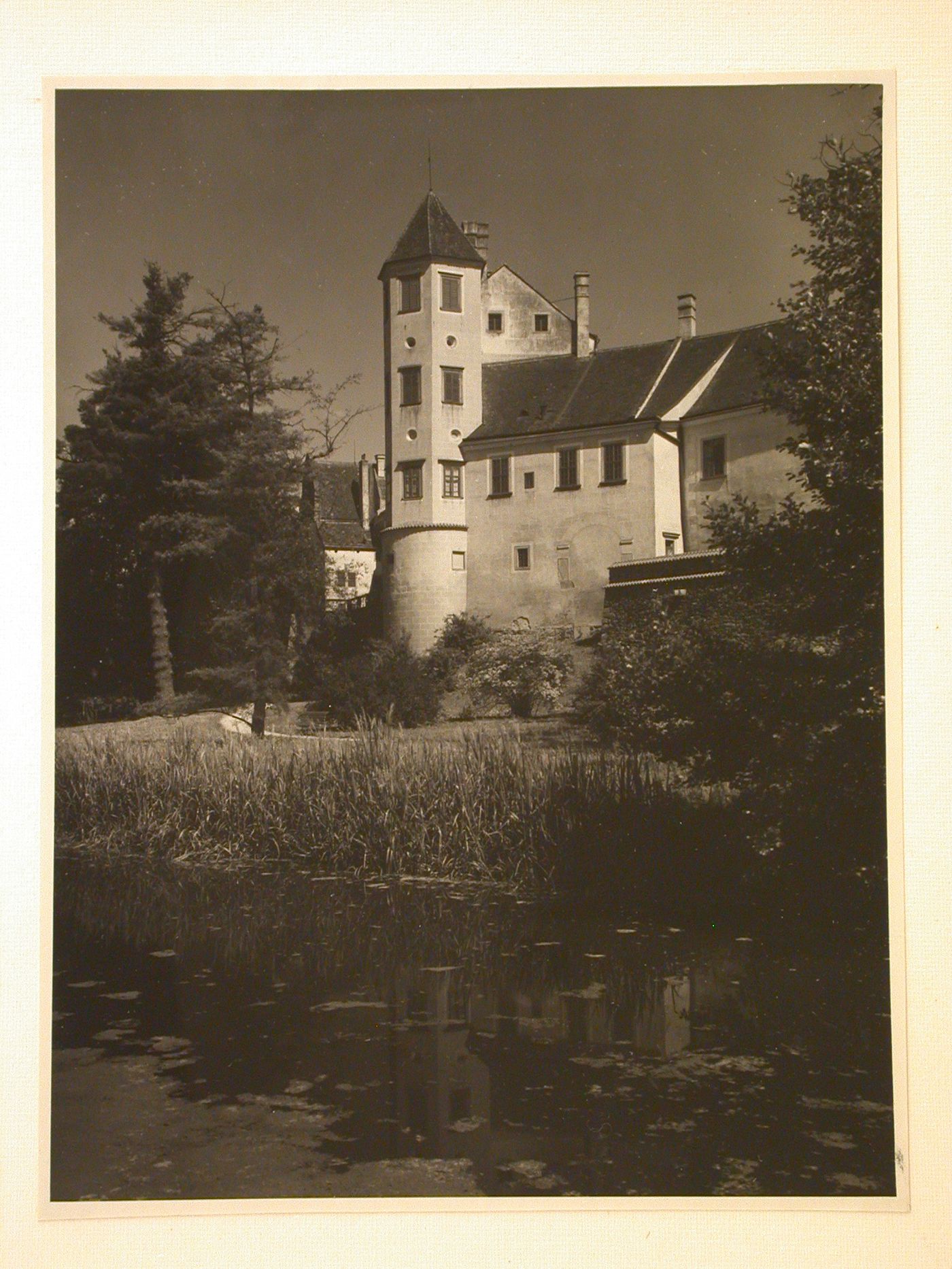 Rear view of buildings and a tower from across a pond, possibly showing a part of Telc Château, Telc, Czechoslovakia (now Czech Republic)