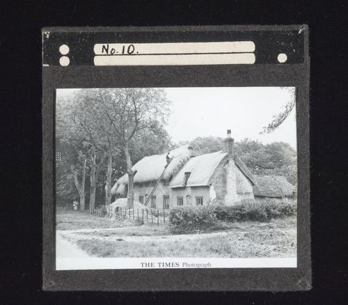 View of croft house with man on ladder working on roof