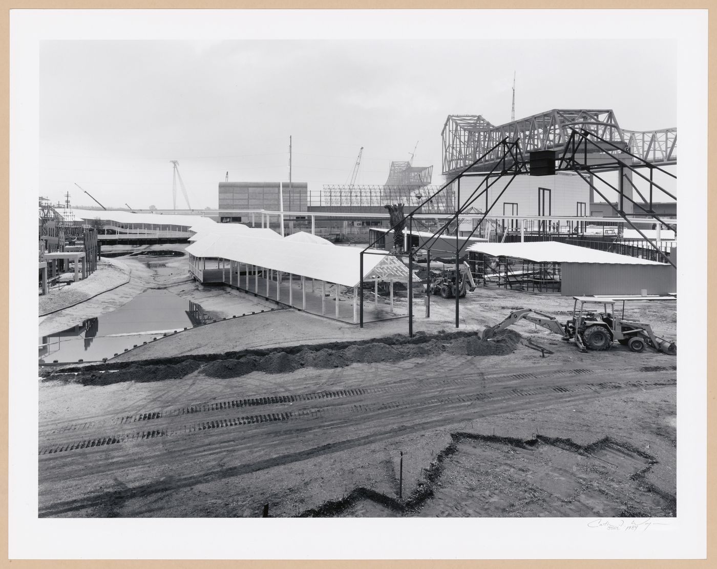 View of the metal framework of the City Gate under construction with covered walkways and the Monorail track in the background, Louisiana World Exposition, New Orleans