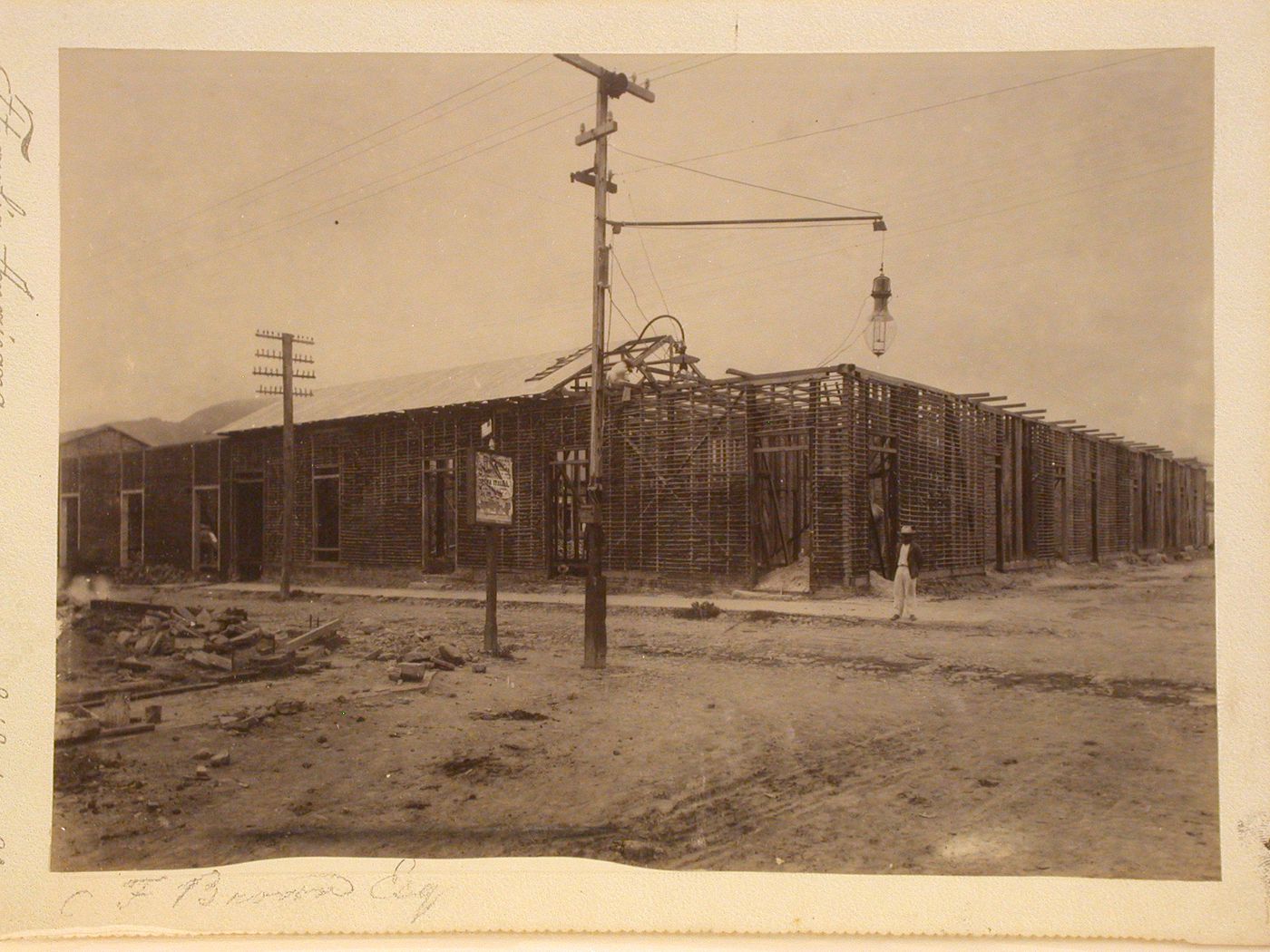 Corner view of housing under construction, man standing on right by corner of buildings