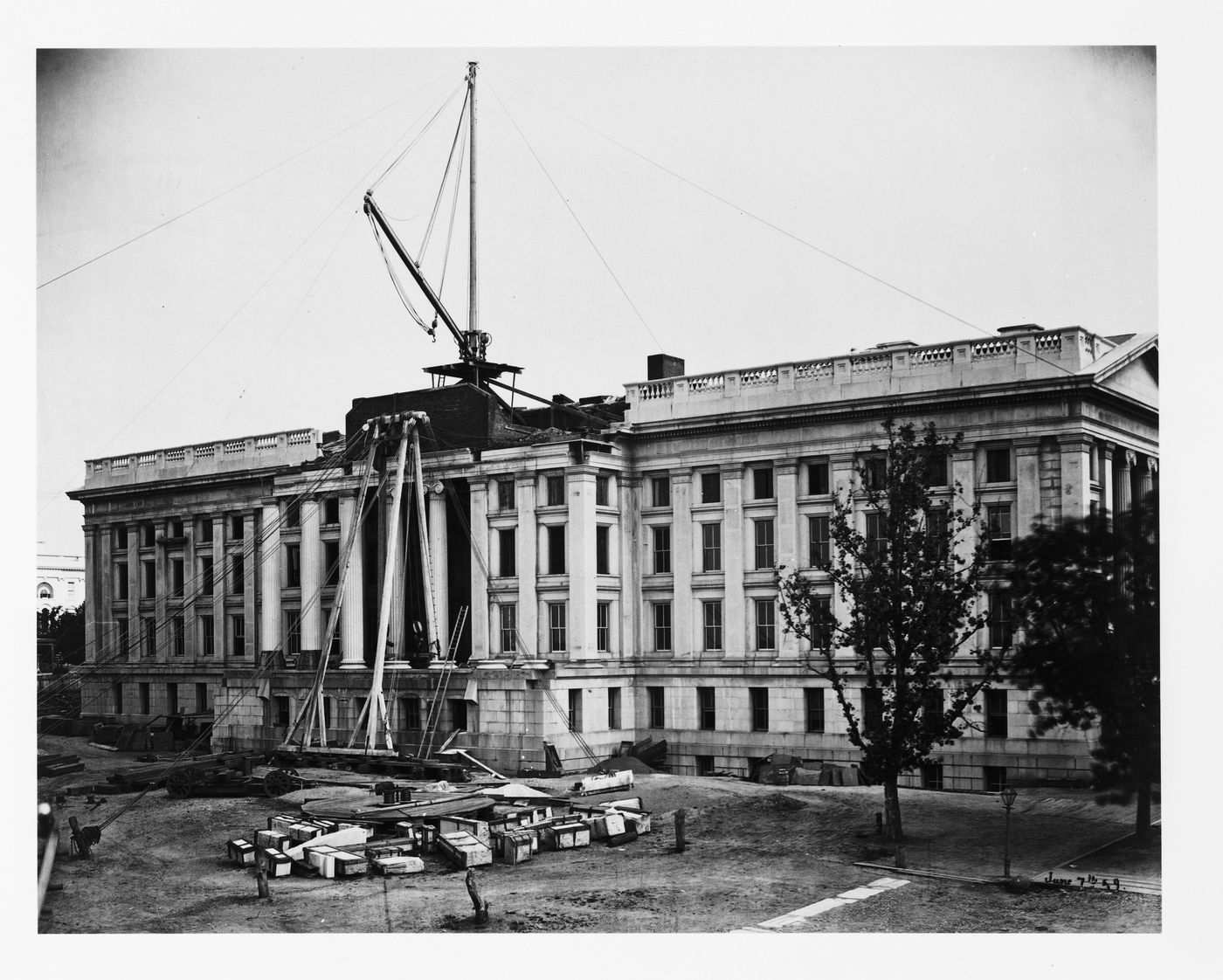 Treasury Building under contruction: View of building with half of roof on, cranes and lines connecting from the ground, Washington, District of Columbia