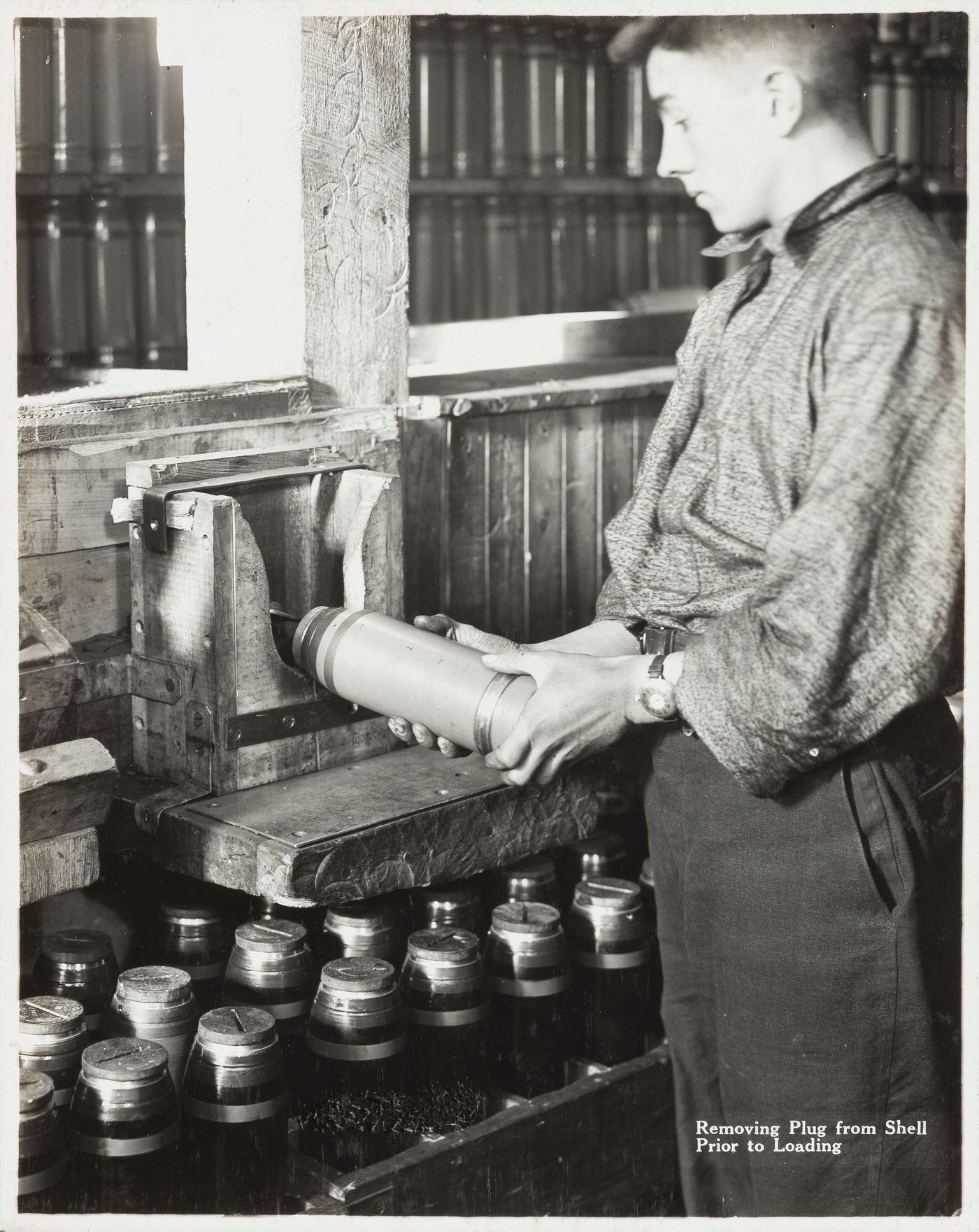Interior view of worker removing plug from shell prior to loading at the Energite Explosives Plant No. 3, the Shell Loading Plant, Renfrew, Ontario, Canada