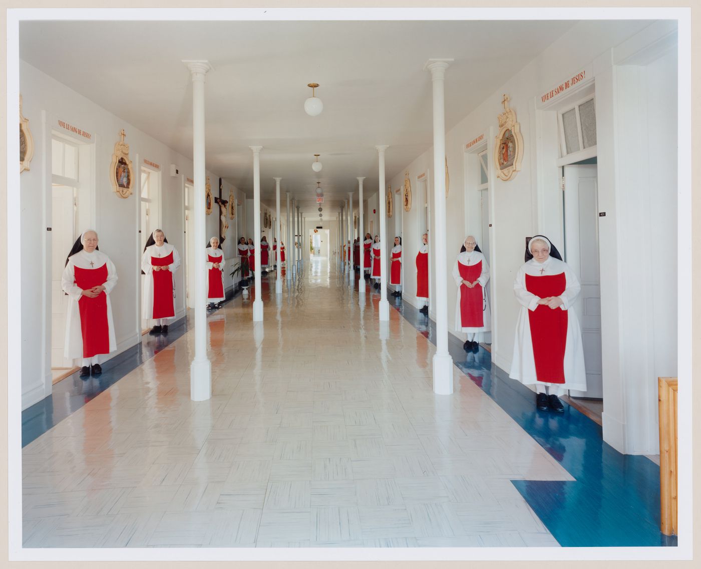 View of interior hallway of cells with the Soeurs Adoratrices du Précieux-Sang standing at doors, from the Convent Series, Nicolet, Québec, Canada