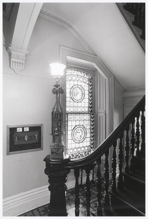 Interior view of the original carved wooden stairs and a stained glass window in the west part of Shaughnessy House, Montréal, Québec