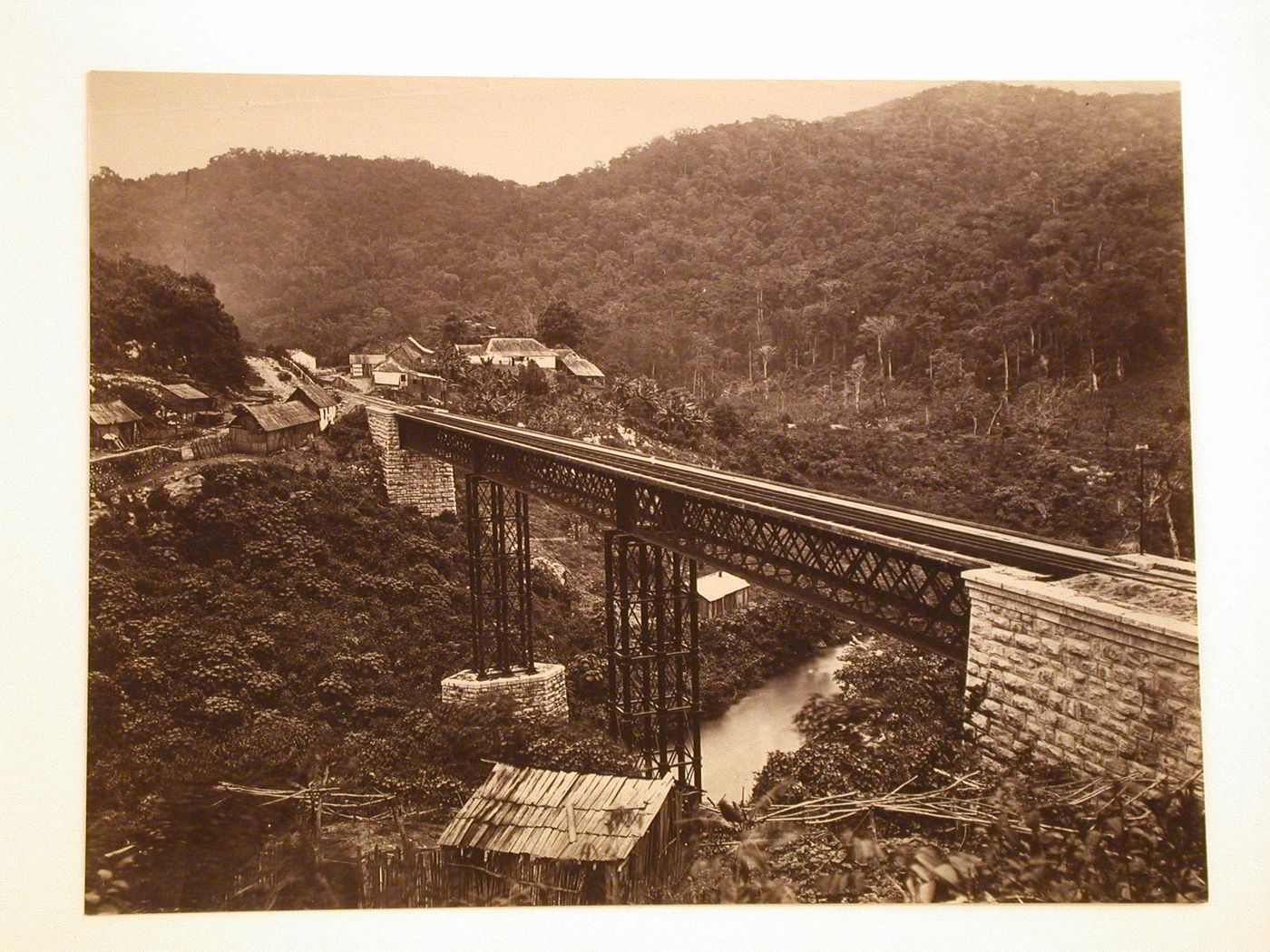 View of the Atoyac railroad bridge and the Atoyac River with huts, a forest and mountains in the background, Mexico