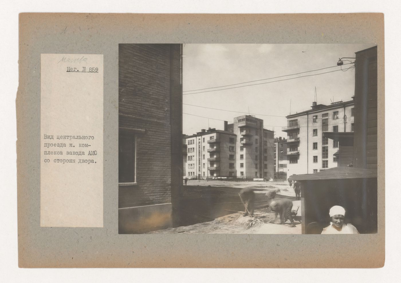 View of a central passage of the AMO (Aktsionernoe mashinostroitel'noe obshchestvo) plant complex showing workers in a courtyard and housing in the background, Moscow