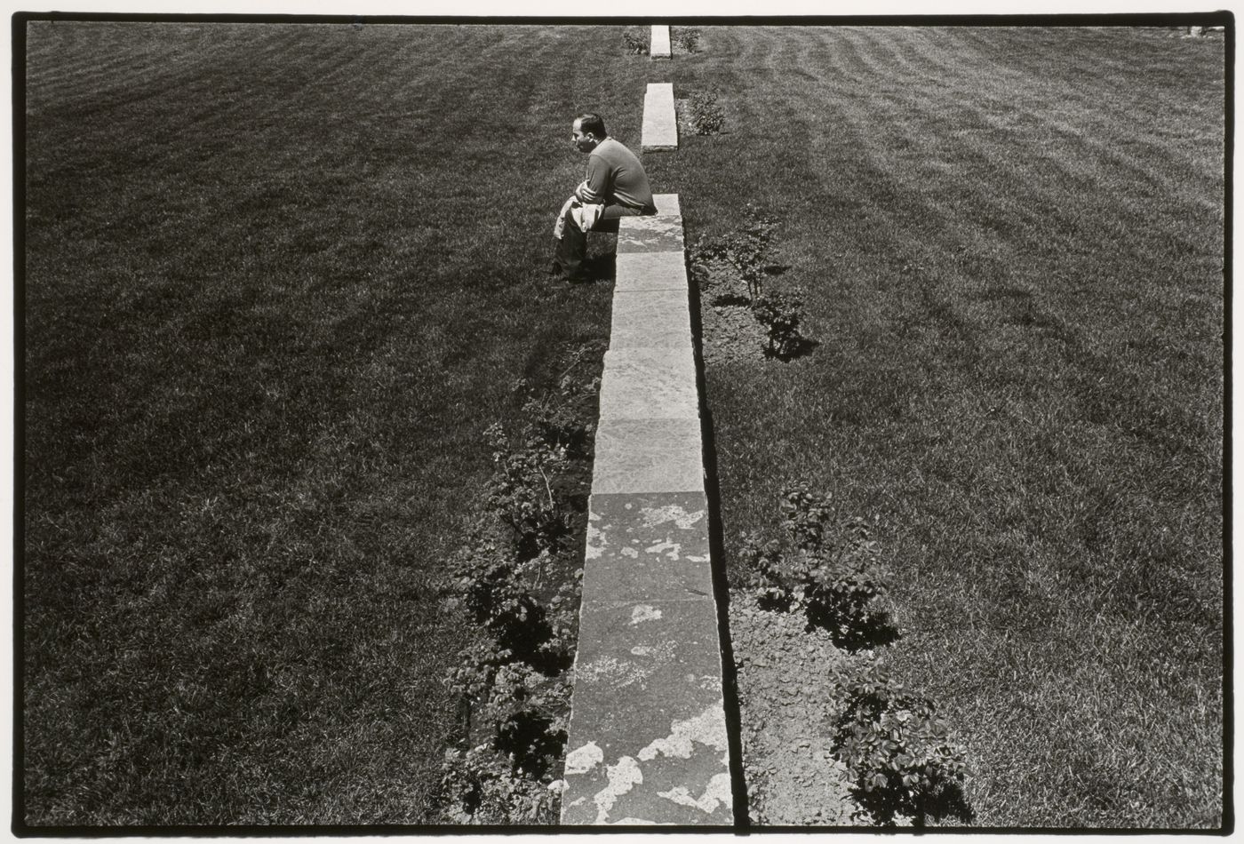 View of a man sitting on one of the cadastral walls which represent rural "rangs" or property lines, CCA garden, Montréal, Québec, Canada