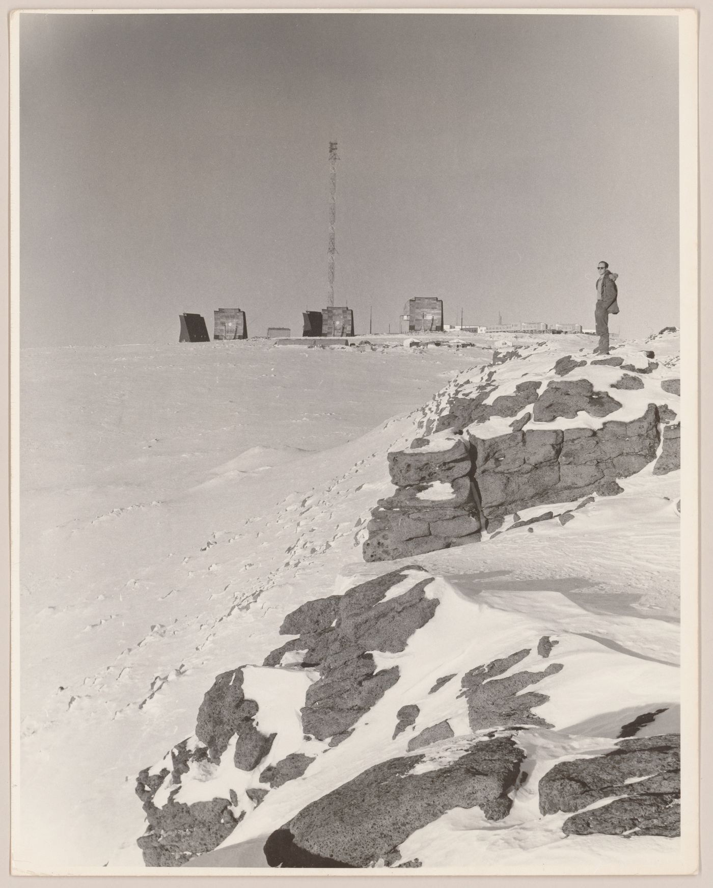 View of DEW Line radar station DYE-Main with person standing on the right, Cape Dyer, Nunavut, Canada