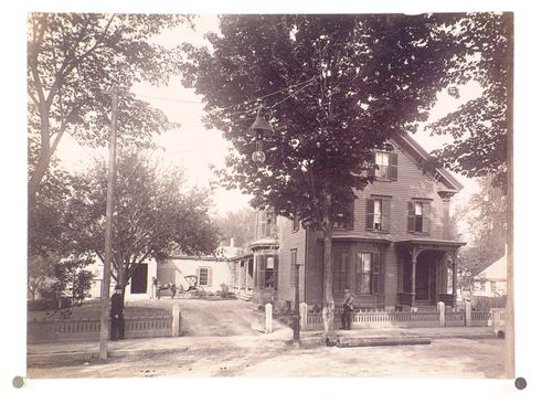 Clapboard house on street, with street light, two figures on sidewalk