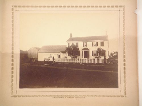 Wooden house with barn attached, fence surrounding front garden, five figures, one with horse