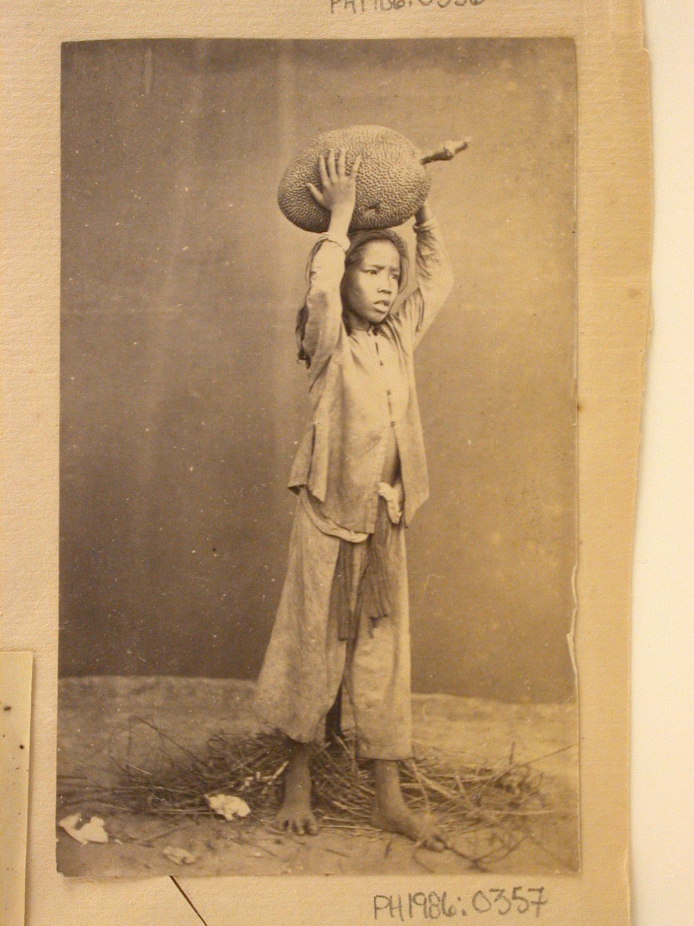 Portrait of a boy holding a durien fruit, probably in Cochin China (now in Vietnam)