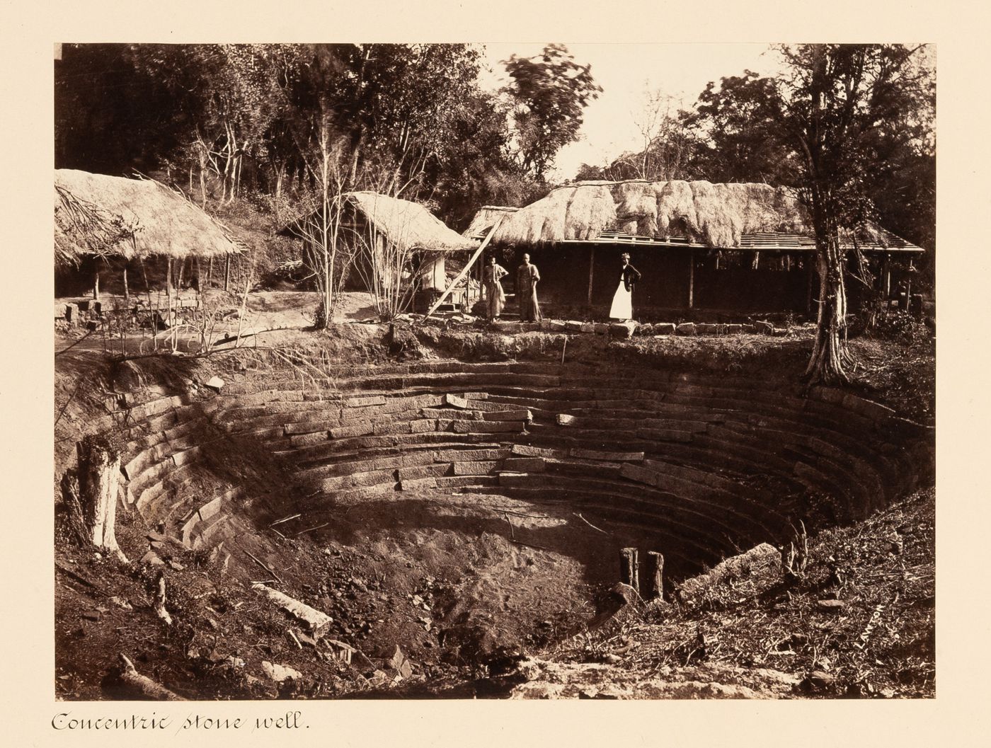 View of a water well with huts in the background, Anuradhapura, Ceylon (now Sri Lanka)