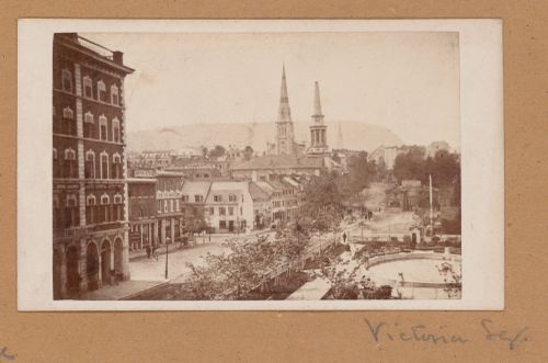 Partial view of Victoria Square showing the fountain, stores, the old YMCA Headquarters on the left and Mount Royal in the background, Montréal, Canada (now Montréal, Québec, Canada)